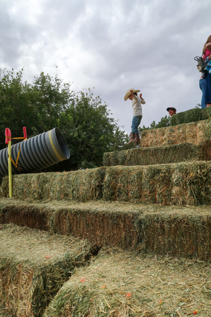 child jumping down hay pyramid